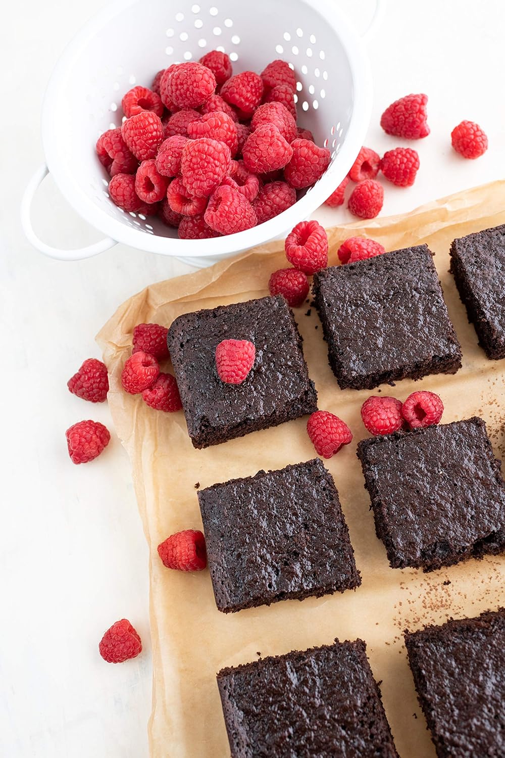 Brownies on a wooden board with raspberries