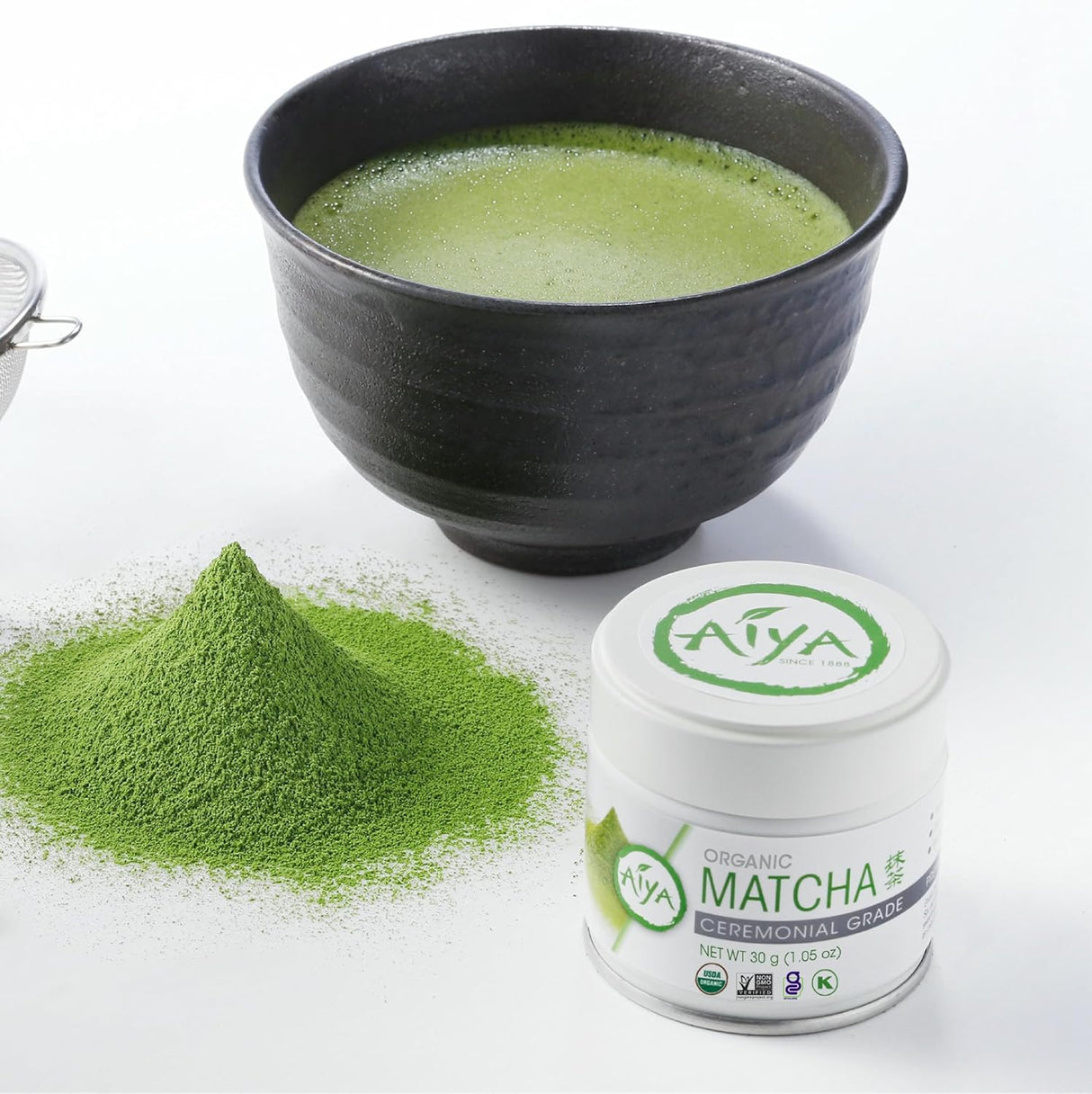 Matcha green tea powder, a bowl of matcha, and a container of AIYA Matcha on a white background