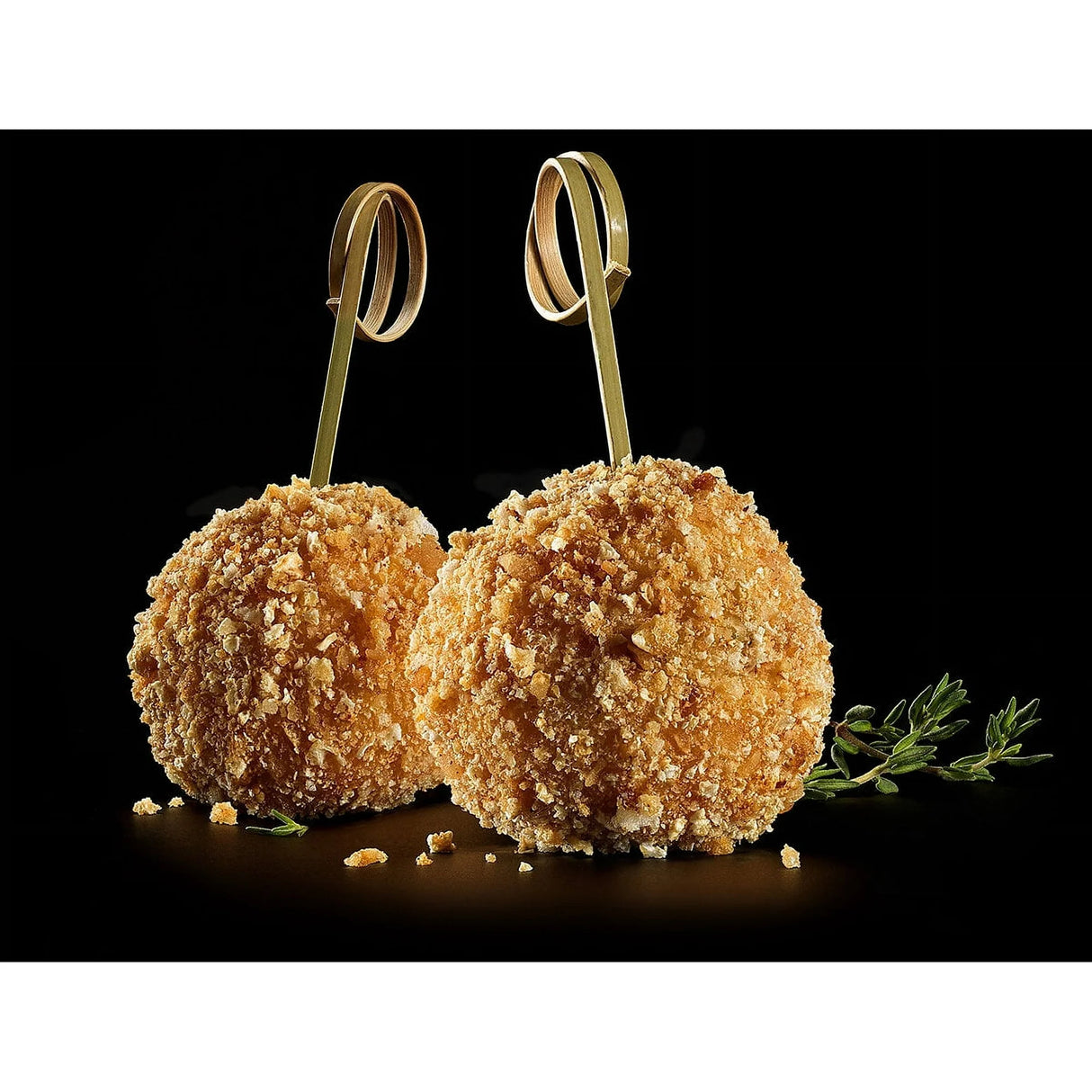 Two breaded food items on skewers with a black background