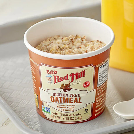 Bob's Red Mill gluten-free oatmeal cup on a white surface with a yellow container in the background.