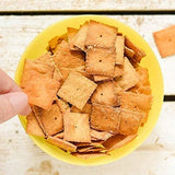 Yellow bowl filled with square crackers on a wooden surface