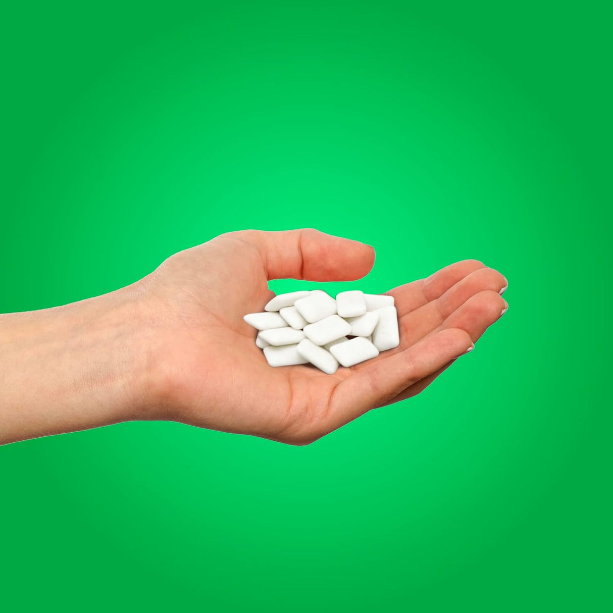 Hand holding white pills against a green background