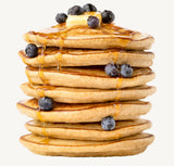 Stack of pancakes with blueberries and syrup on a white background