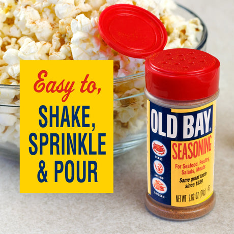 Old Bay seasoning bottle with red lid and yellow label next to a bowl of popcorn.