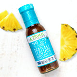 Bottle of Primal Kitchen No Soy Island Teriyaki Organic Sauce & Marinade with pineapple slices on a white background
