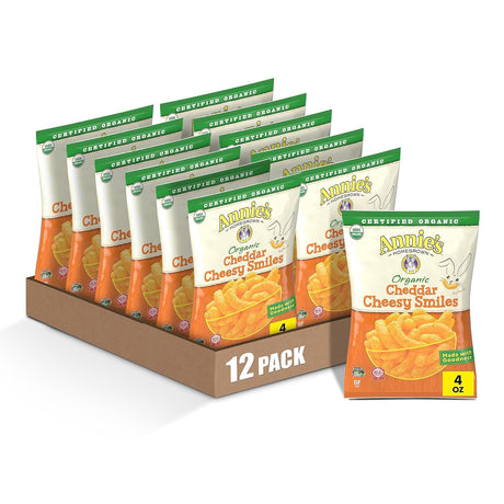Display of Annie's Organic Cheddar Cheesy Smiles packaging with a 12-pack box on a white background.