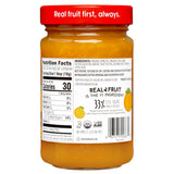 Jar of fruit spread with a red lid and nutrition label on a white background