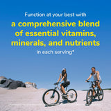 Two people riding bicycles on a beach with a blue sky, promoting vitamins and minerals.
