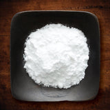 White powdery substance in a black square bowl on a wooden surface