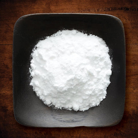 White powdery substance in a black square bowl on a wooden surface