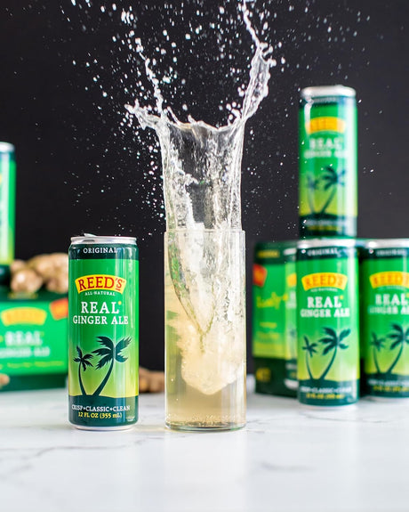Reed's Real Ginger Ale cans with a glass of ginger ale being poured against a black background