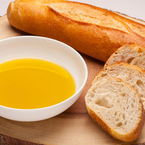 Baguette slices with a bowl of olive oil on a wooden board