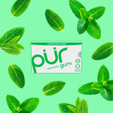 Pur gum packaging with spearmint leaves on a green background