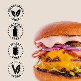 Vegan burger with cheese and vegetables on a bun, featuring 'preservative free', 'lactose free', 'wheat free', and 'vegan' labels on a beige background.