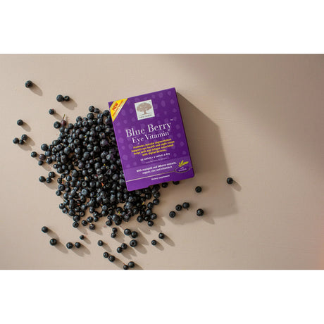 Purple package of Blueberry Eye Vitamin surrounded by blueberries on a beige surface