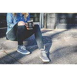 Person sitting on steps holding a coffee cup, wearing jeans and sneakers.