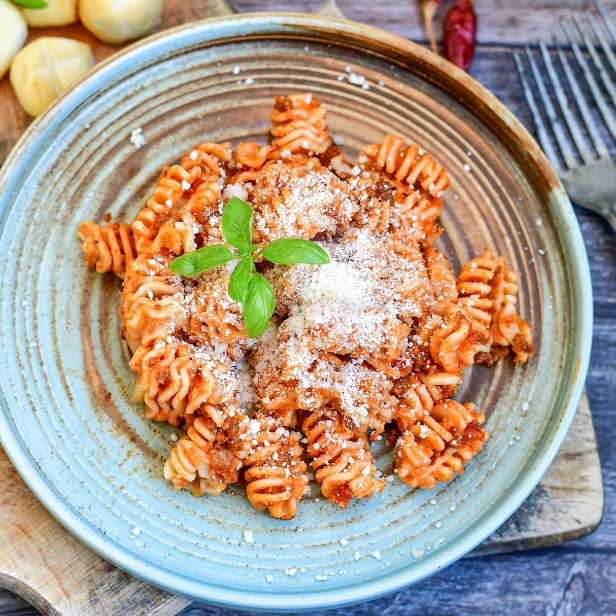 Pasta dish with red sauce and parmesan cheese on a blue plate