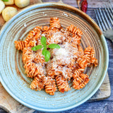 Pasta dish with red sauce and parmesan cheese on a blue plate