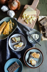 Assorted food items including cheese, bread, and spreads on a wooden table.