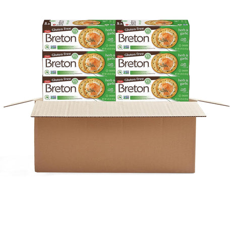 Multiple boxes of Breton gluten-free herb & garlic crackers stacked on a cardboard box.
