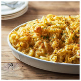 Macaroni and cheese dish with breadcrumb topping in a white dish on a wooden table.