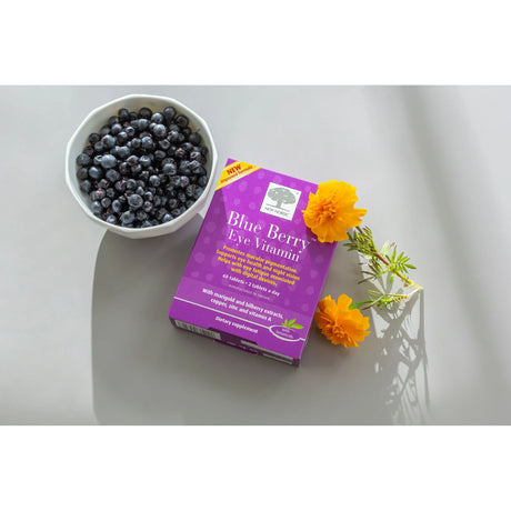 Blueberry eye vitamin package with a bowl of blueberries and flowers on a light surface