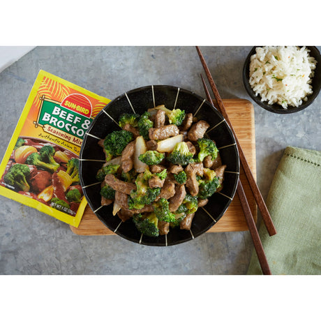 Beef and broccoli stir-fry in a black bowl with Sunbird seasoning mix on a gray surface.
