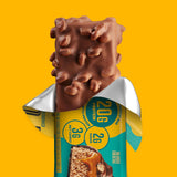 Chocolate-covered snack bar with a partially peeled wrapper on a yellow background
