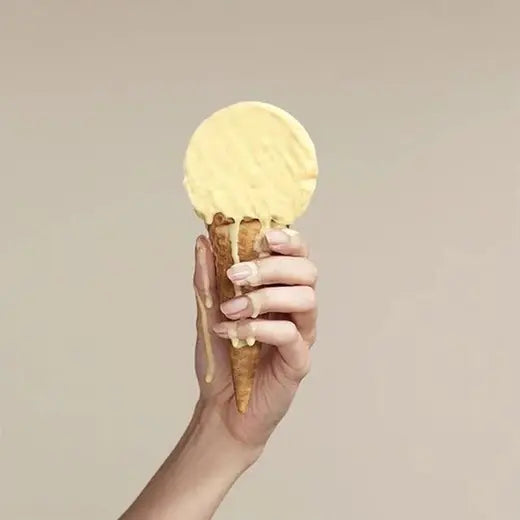 Hand holding a ice cream cone against a plain background