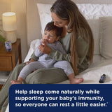 Woman holding a child on a bed with a text overlay about supporting baby's immunity.