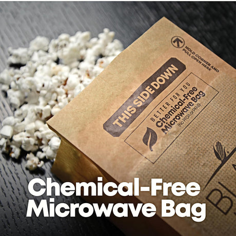 Kraft paper microwaveable popcorn bag with text on a wooden surface with popped popcorn.