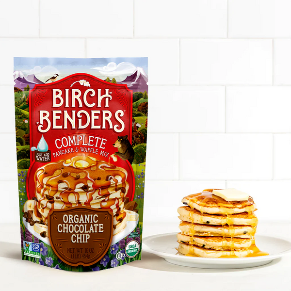 Birch Benders Organic Chocolate Chip pancake mix packaging with a stack of pancakes on a white plate.