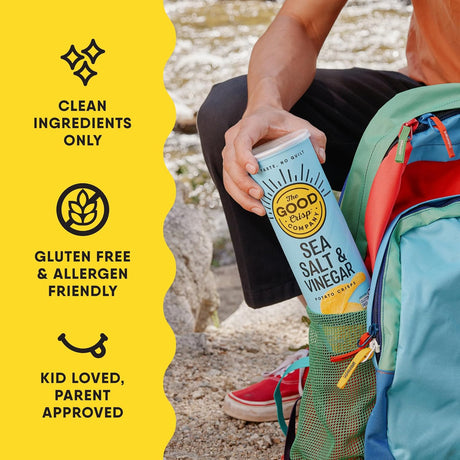 Person holding a can of 'The Good Crisp' potato chips with product details on a yellow background.
