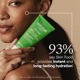 Woman holding a Weleda Skin Food tube with a beige background