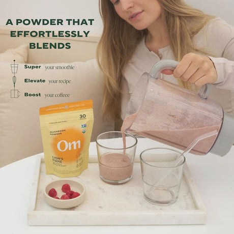 Woman pouring a smoothie into a glass with Om Superfood Powder packaging on a table.