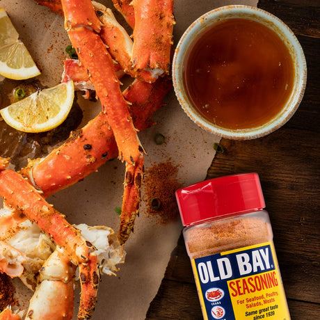 Crab legs with Old Bay seasoning and lemon wedges on a wooden surface