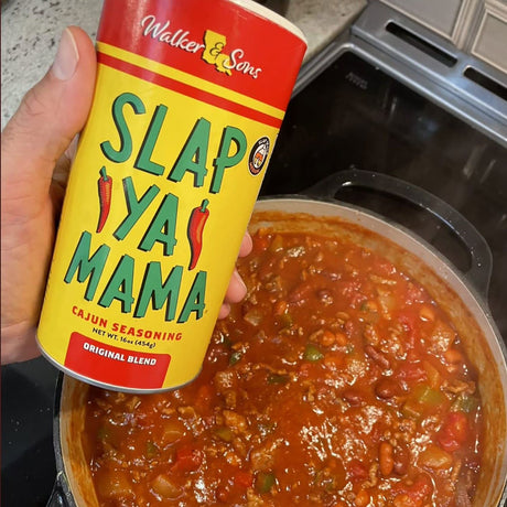 Can of Walker & Sons Slap Ya Mama Cajun seasoning held over a pot of stew.