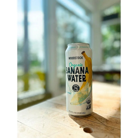 Can of Woodstock Organic Banana Water on a wooden surface with a blurred background
